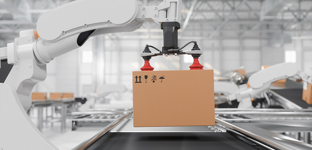 Side view of a white robotic arm with red vacuum grippers carrying a cardboard box on a conveyor belt in a smart distribution warehouse
