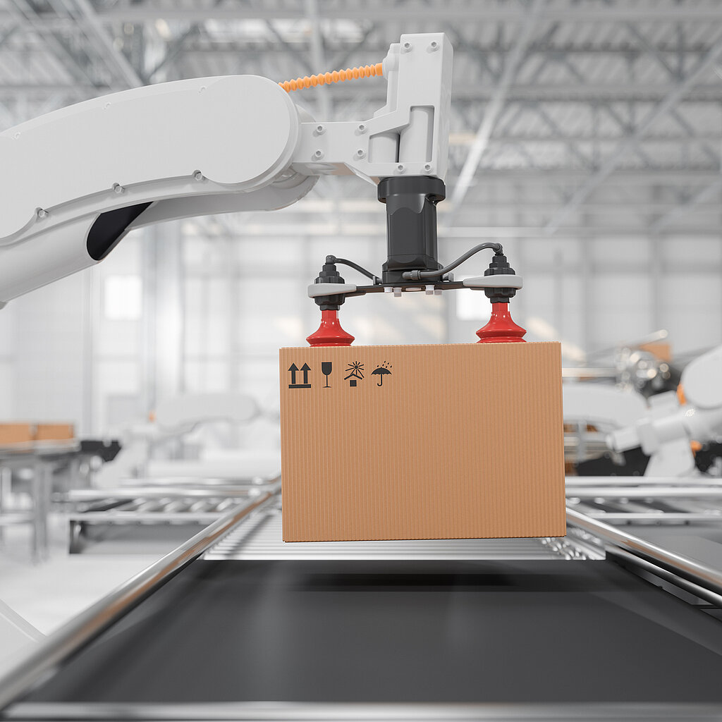Side view of a white robotic arm with red vacuum grippers carrying a cardboard box on a conveyor belt in a smart distribution warehouse